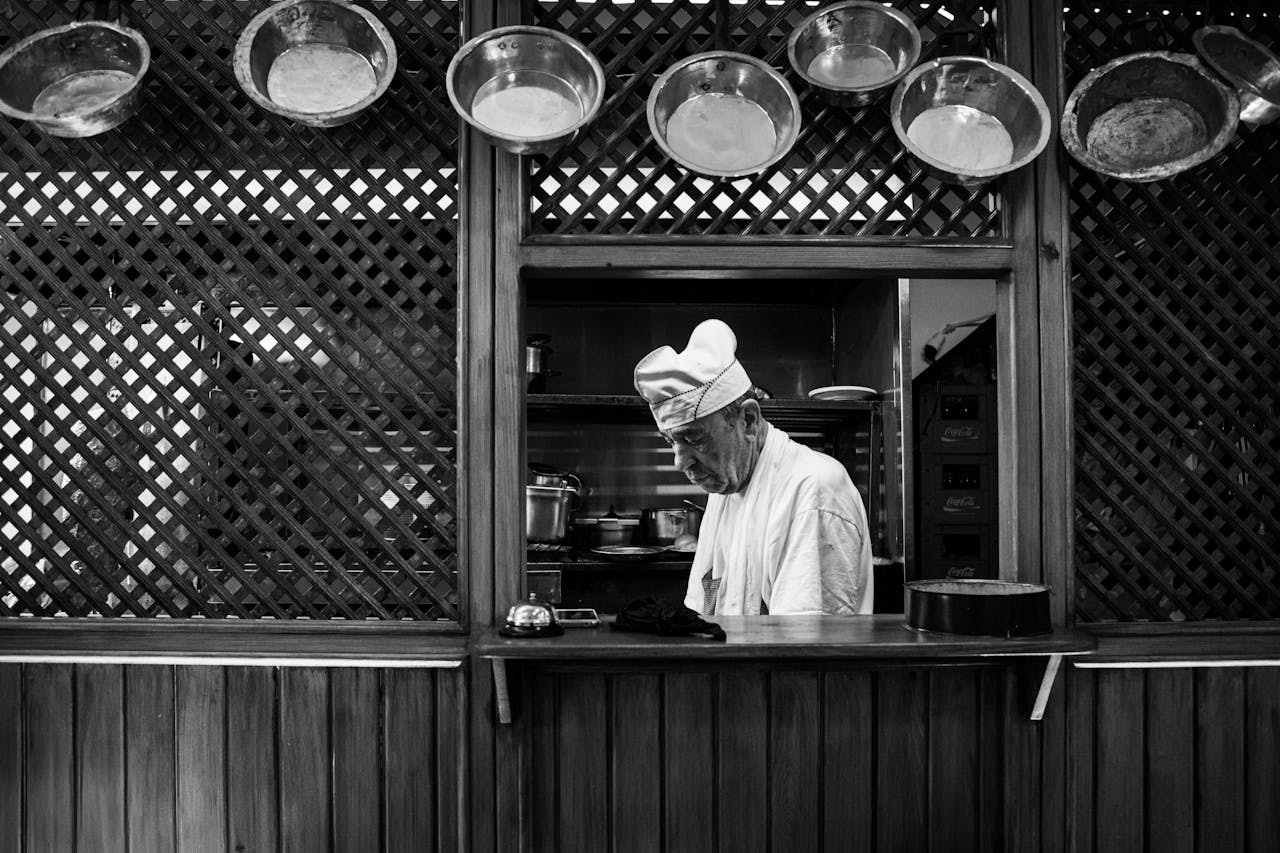 Black and white photo of a chef in a traditional kitchen setting in Bursa, Türkiye.